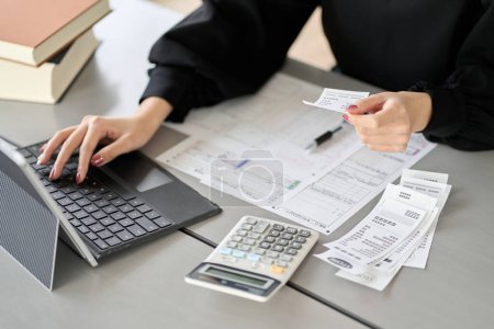Téléchargez les photos : Asian woman entering expenses in accounting software - en image libre de droit