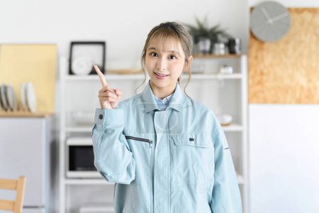 Téléchargez les photos : Une femme professionnelle en vêtements de travail pointant du doigt la maison de quelqu'un - en image libre de droit