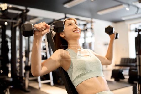 Photo for Woman training her chest with dumbbell presses - Royalty Free Image