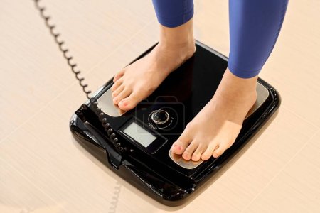 Foto de Una mujer que usa una escala de grasa corporal en el gimnasio - Imagen libre de derechos