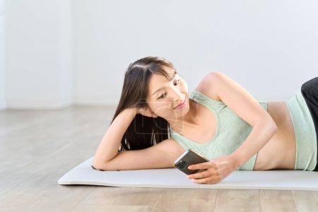 Photo for Woman looking at smartphone during training break - Royalty Free Image