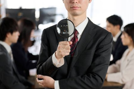 Photo for Asian businessman holding a magnifying glass and uncovering fraud - Royalty Free Image