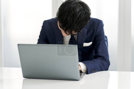 Téléchargez les photos : Homme d'affaires pendu la tête devant un ordinateur - en image libre de droit