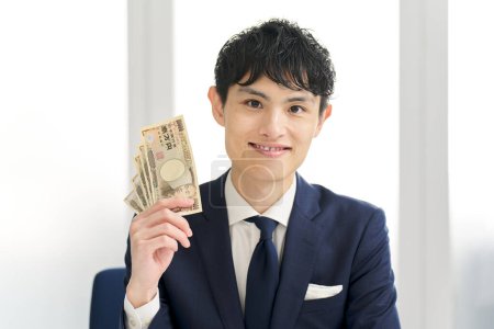 Asiatischer Geschäftsmann lächelt und hält Geld