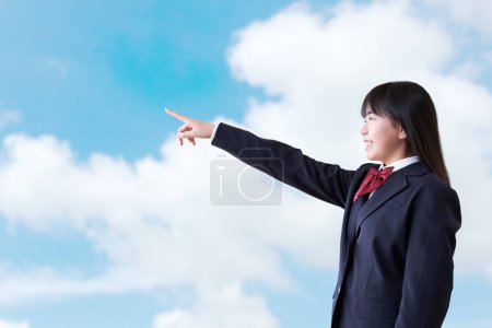 Female student pointing under the blue sky
