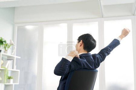 Rear view of a businessman stretching while working