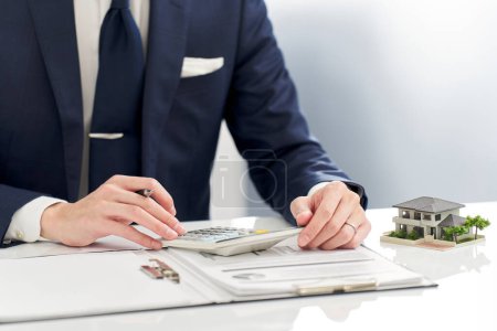 Téléchargez les photos : Homme d'affaires calculant de l'argent lié à l'immobilier - en image libre de droit