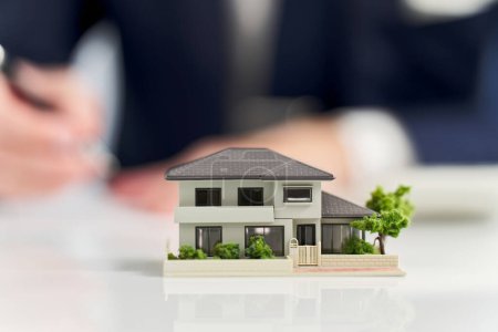 Miniaturmodell eines Hauses und eines Geschäftsmannes
