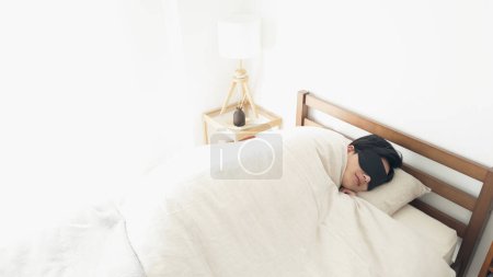Ein Mann schläft mit Augenmaske in einem hellen Raum