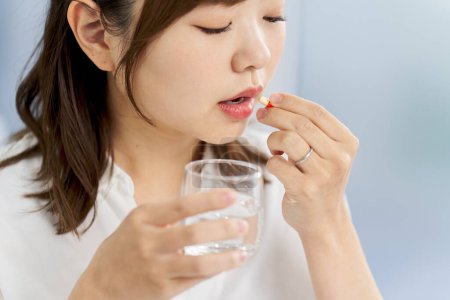 Foto de Mujer asiática bebiendo medicina cápsula - Imagen libre de derechos