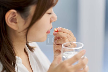 Foto de Mujer asiática bebiendo medicina cápsula - Imagen libre de derechos