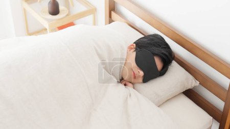 Téléchargez les photos : Un homme dort avec un masque oculaire dans une pièce lumineuse - en image libre de droit