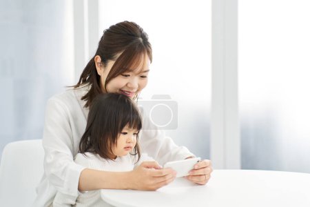 Photo for Girl looking at smartphone with mom - Royalty Free Image