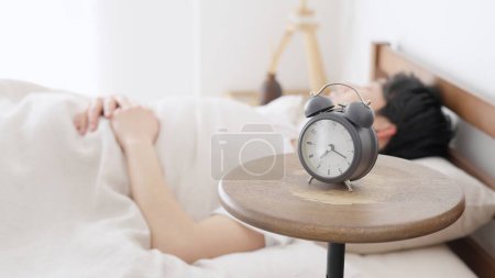 A man sets an alarm clock and sleeps