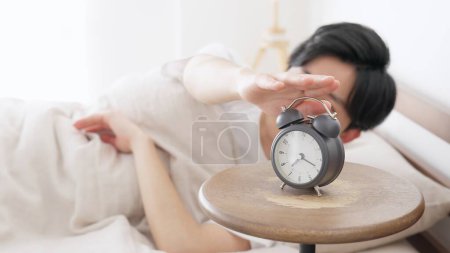 A man stops a ringing alarm clock