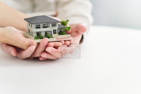 Photo for Hands of a man and woman holding a model of a house - Royalty Free Image