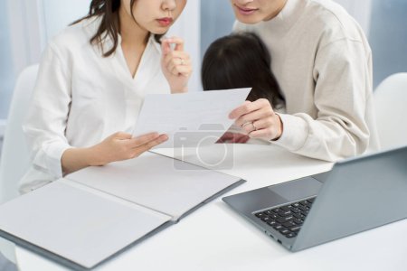 Famille asiatique envisageant d'acheter une assurance