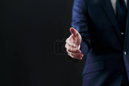Geschäftsmann bittet um Handschlag auf schwarzem Hintergrund