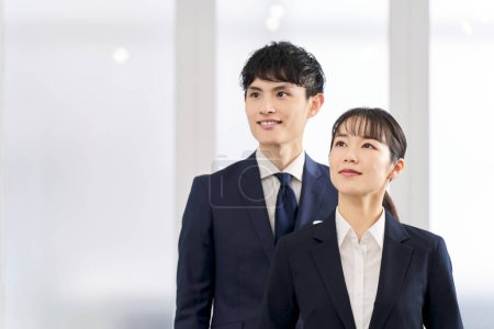 Male and female business people looking up in the office
