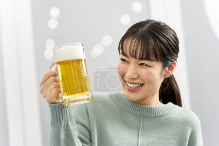 Woman drinking beer from mug at home