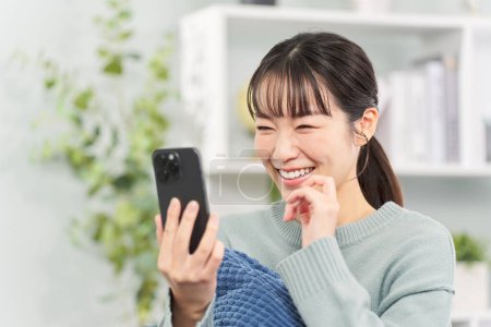 Woman sitting on sofa and looking at smartphone