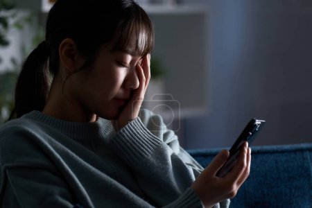 Eine depressive Frau blickt auf ihr Smartphone
