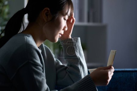 Una mujer deprimida mirando su libreta en un cuarto oscuro