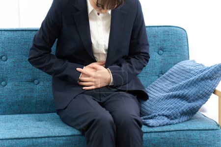 Eine Frau hat Bauchschmerzen, bevor sie zur Arbeit geht