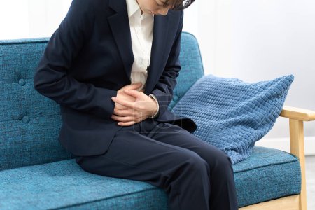 Eine Frau hat Bauchschmerzen, bevor sie zur Arbeit geht