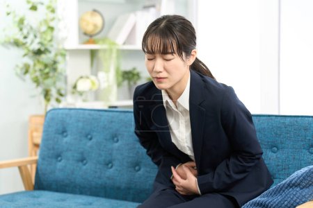 Foto de Una mujer siente dolor de estómago antes de ir a trabajar - Imagen libre de derechos