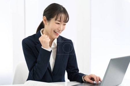 A woman doing a fist pump in front of a computer