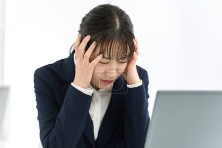 Femme d'affaires tenant la tête devant un ordinateur