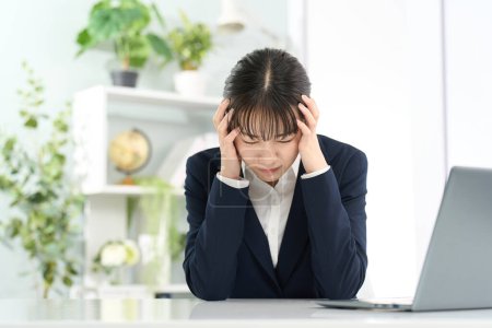 Business woman holding her head in front of a computer