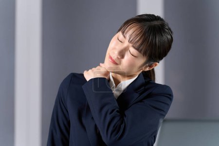 A business woman with stiff shoulders due to overtime work