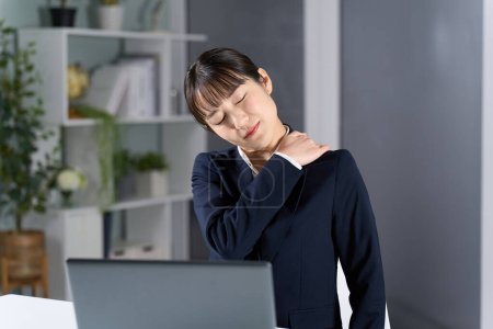 Una mujer de negocios con hombros rígidos debido al trabajo de horas extras