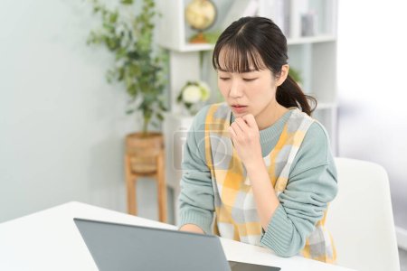 Eine Frau mit Schürze, die sich Sorgen um die Arbeit am Computer macht