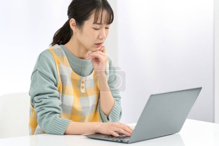 Eine Frau mit Schürze, die sich Sorgen um die Arbeit am Computer macht