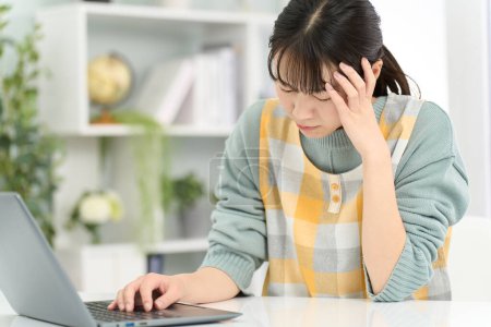 Eine Frau mit Schürze hält ihren Kopf während der Arbeit am Computer