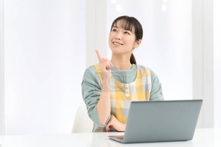 A woman wearing an apron comes up with good ideas while working on a computer