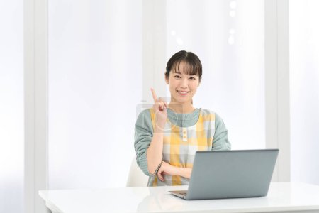 Une femme portant un tablier vient avec de bonnes idées tout en travaillant sur un ordinateur