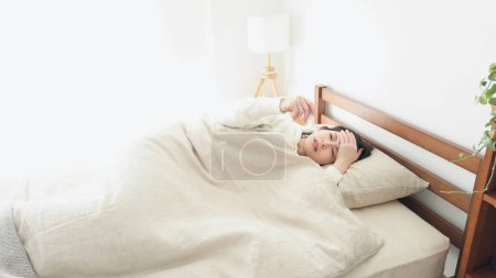 Eine Frau misst im Schlaf ihre Temperatur mit einem Thermometer