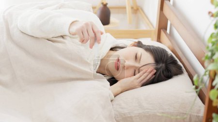 Une femme mesure sa température avec un thermomètre pendant qu'elle dort