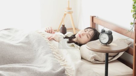 Mujer poniendo un despertador y yendo a dormir