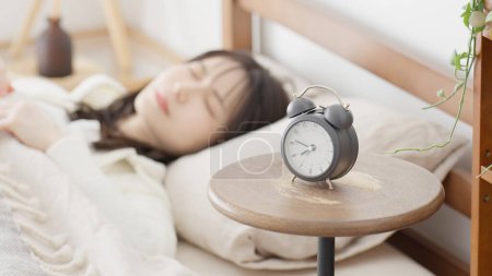 Woman setting an alarm clock and going to sleep