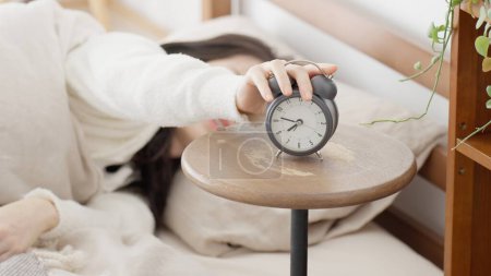A woman who turns off her alarm clock in the morning