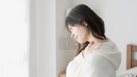 Eine Frau kümmert sich um ihre schmerzende Schulter