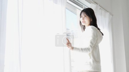 Una mujer abriendo las cortinas por la mañana