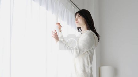 Une femme ouvre les rideaux le matin
