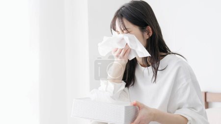 Woman blowing her nose in the room