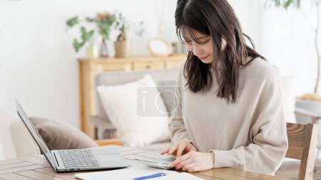 Une femme calculant avec une calculatrice et prenant des notes